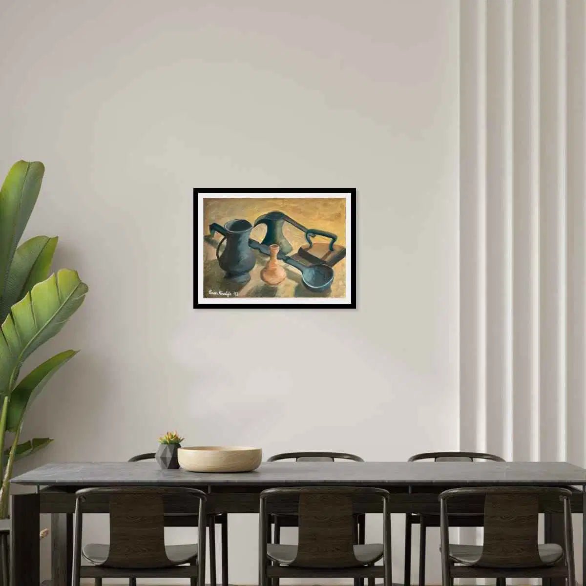 Framed artwork of three ceramic pots on a wall above a dining table with chairs.