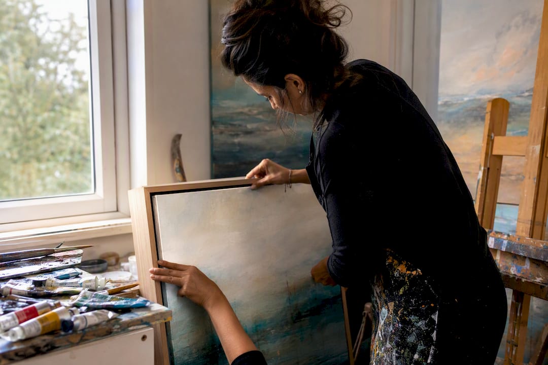 Artist mounting canvas in floating frame