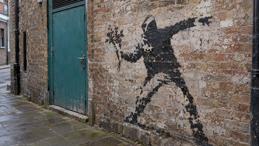 Hooded flower-throwing stencil on a city wall