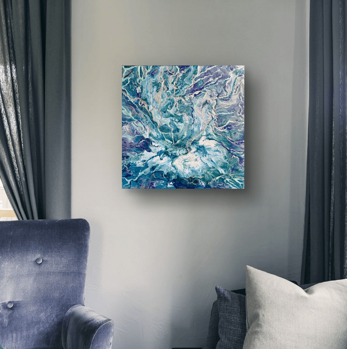 Abstract canvas wall art featuring swirling teal, blue, and purple marbled patterns, displayed on a light gray wall in a modern living room setting with a blue armchair and dark curtains.