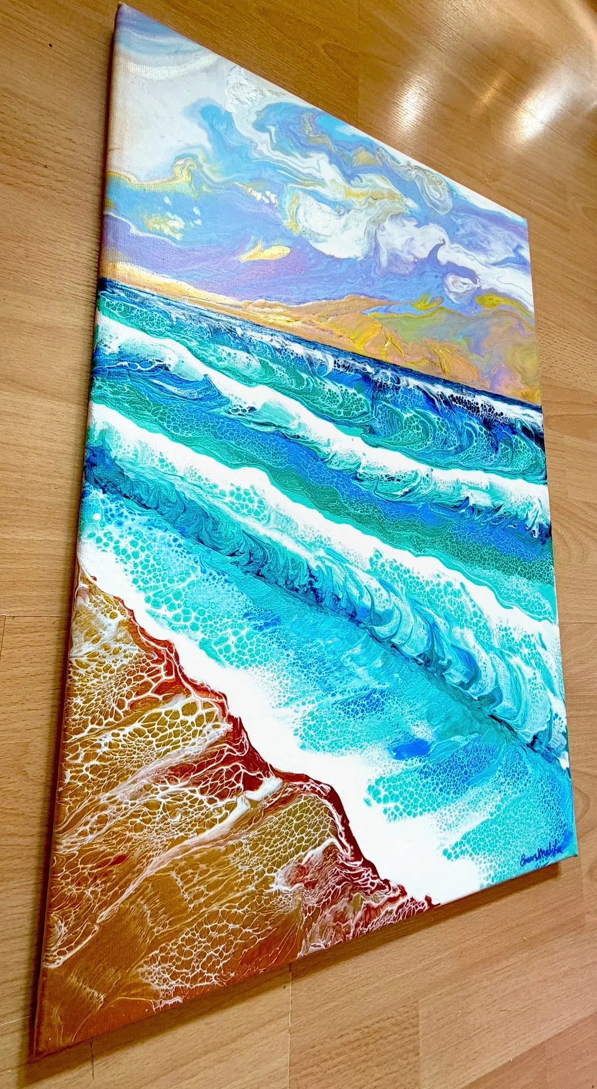 Canvas painting of a beach scene with waves and sky on a wooden surface