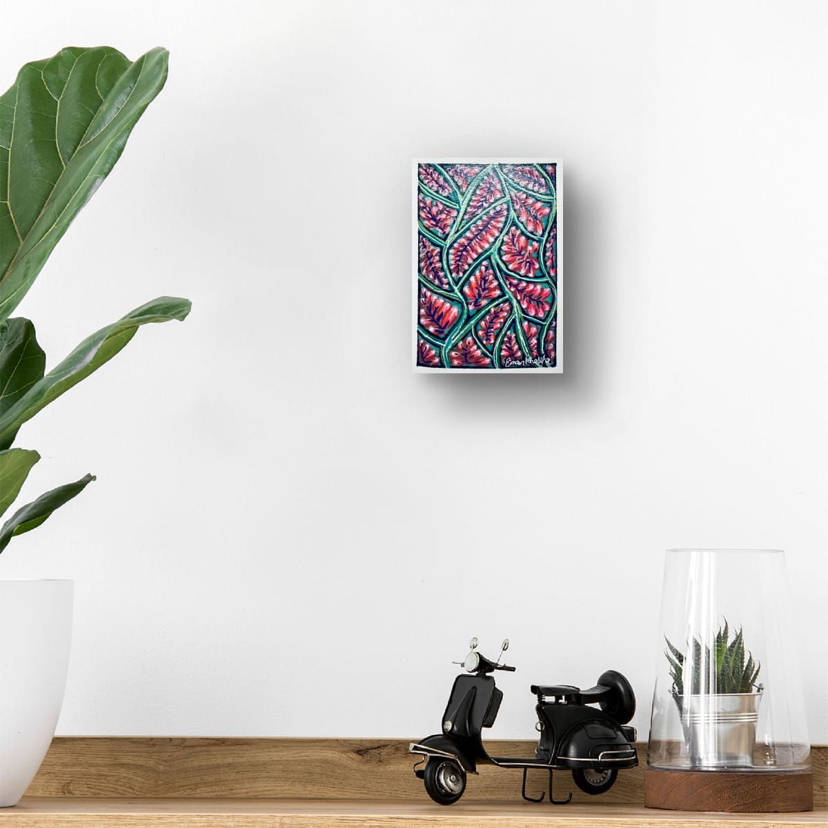 Decorative wall art A6 original acrylic painting featuring a vibrant floral bloom pattern with red blossoms and green botanical lines by Eman Khalifa, on a white wall with a small black scooter model and plant below.