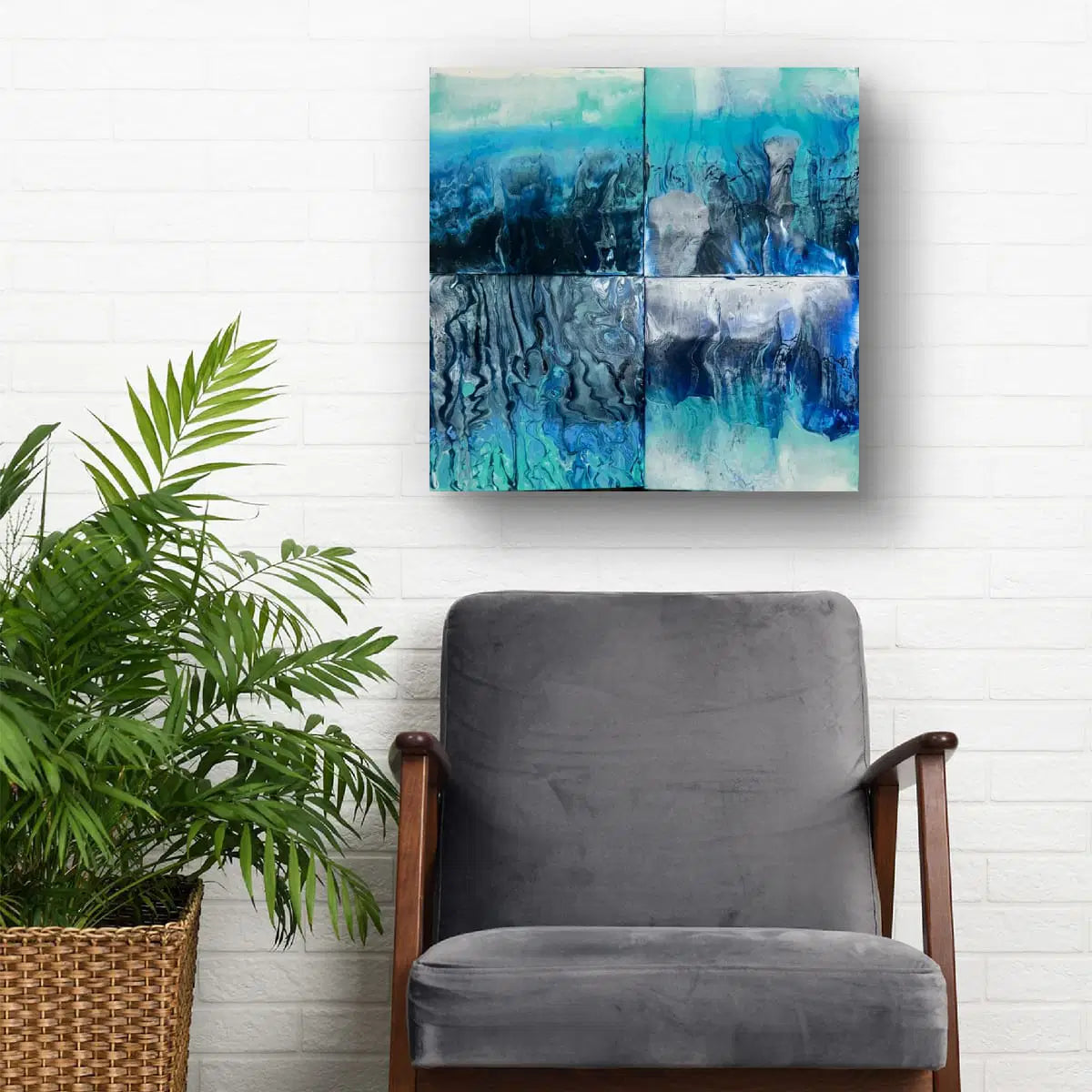 Gray armchair with a plant and abstract blue artwork on a white brick wall