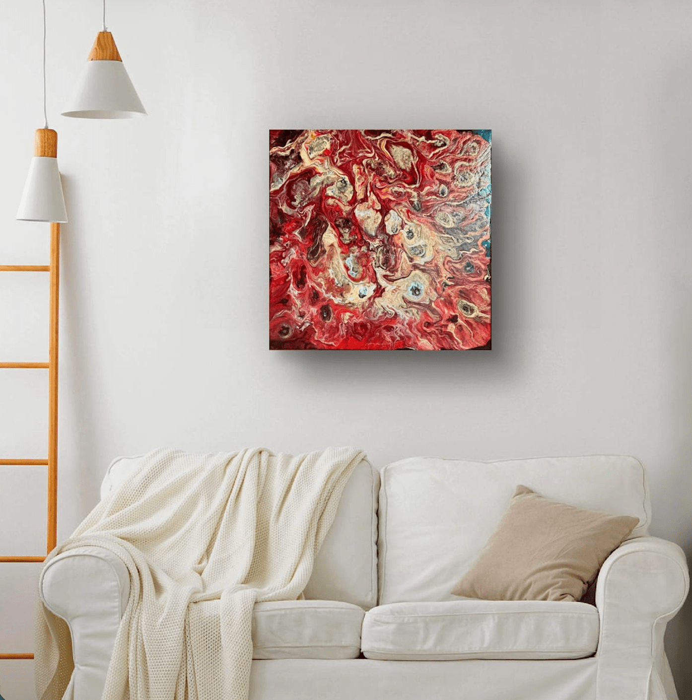 Abstract square canvas wall art with swirling red, gold, copper, and crimson paint, displayed above a white sofa in a modern living room setting.