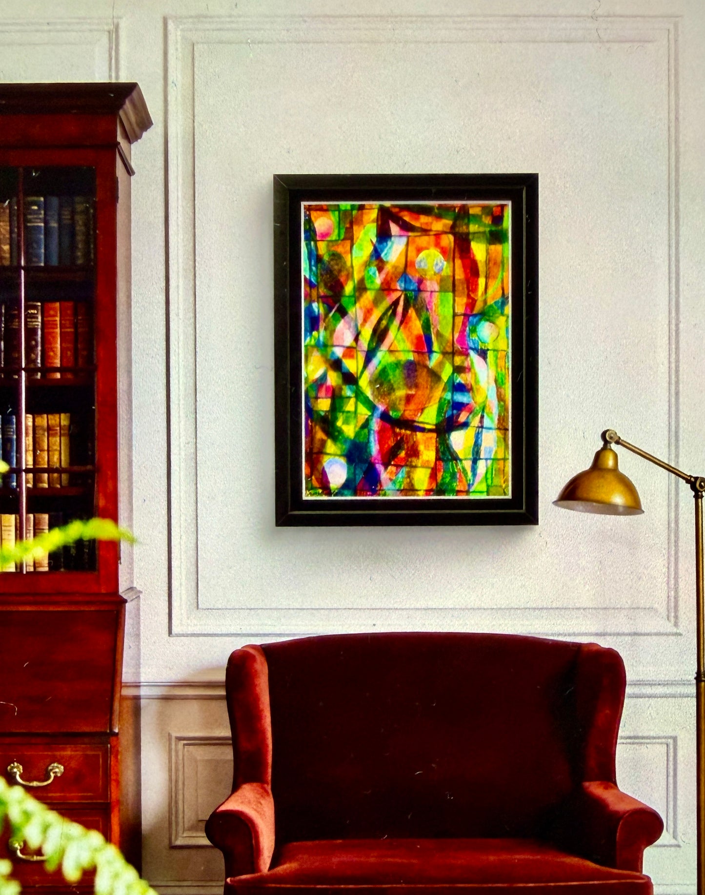 Colorful abstract painting on a wall above a red armchair in a room with a bookshelf and lamp.