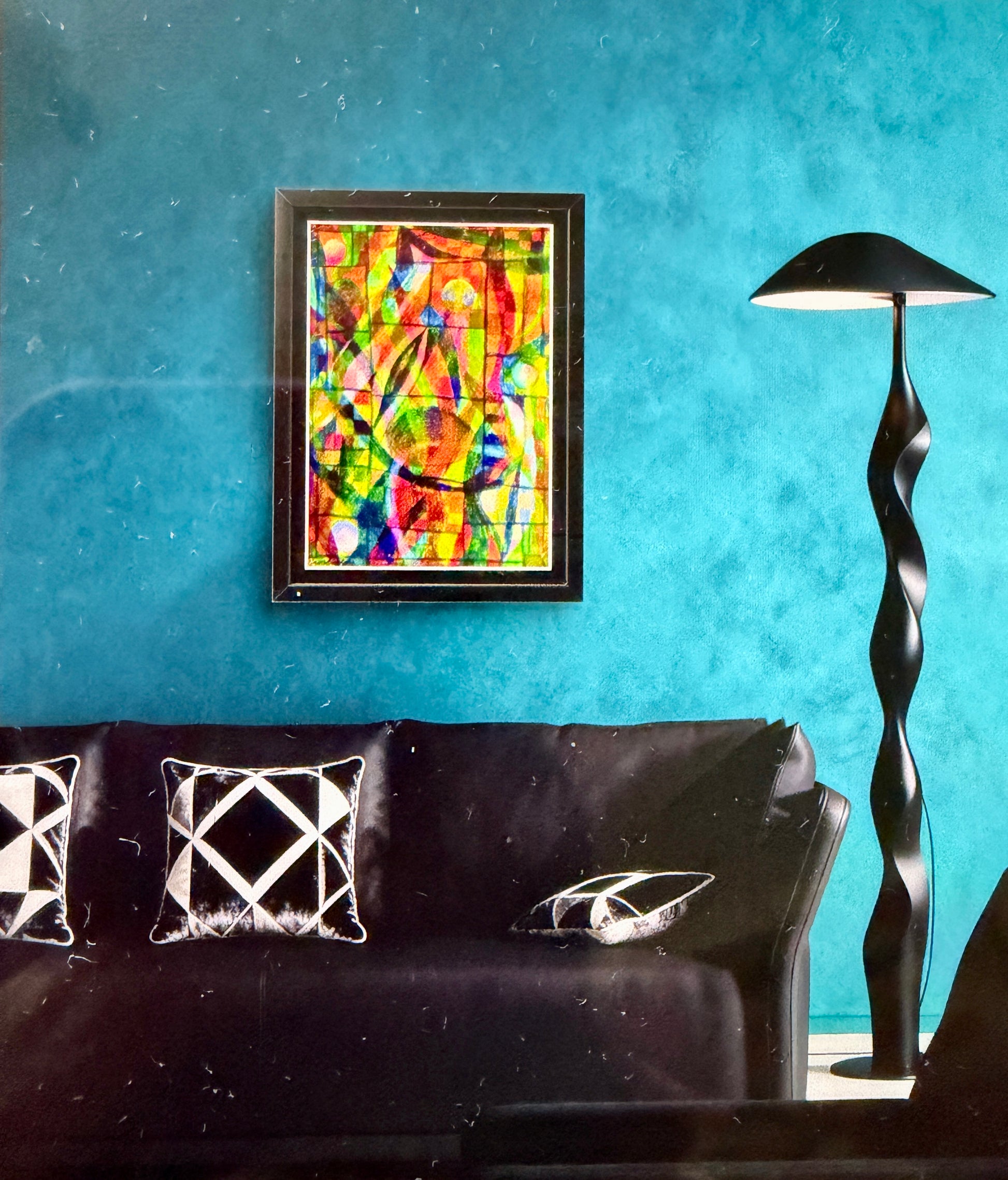 Colorful abstract painting on a blue wall above a black sofa with decorative pillows.
