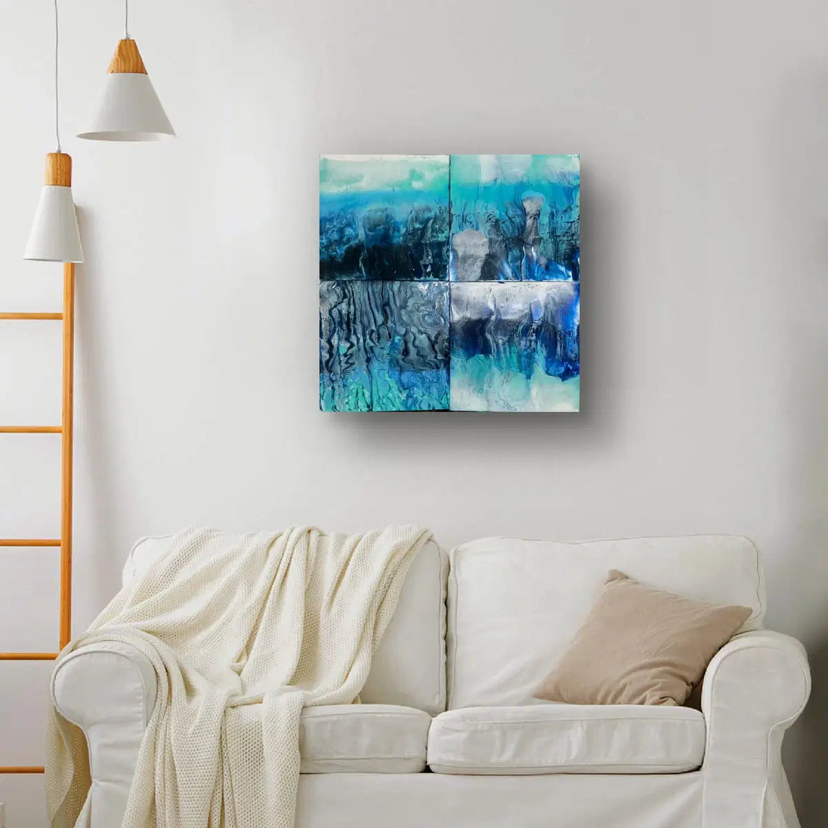 Abstract blue and green painting on a wall above a white sofa with a beige pillow.
