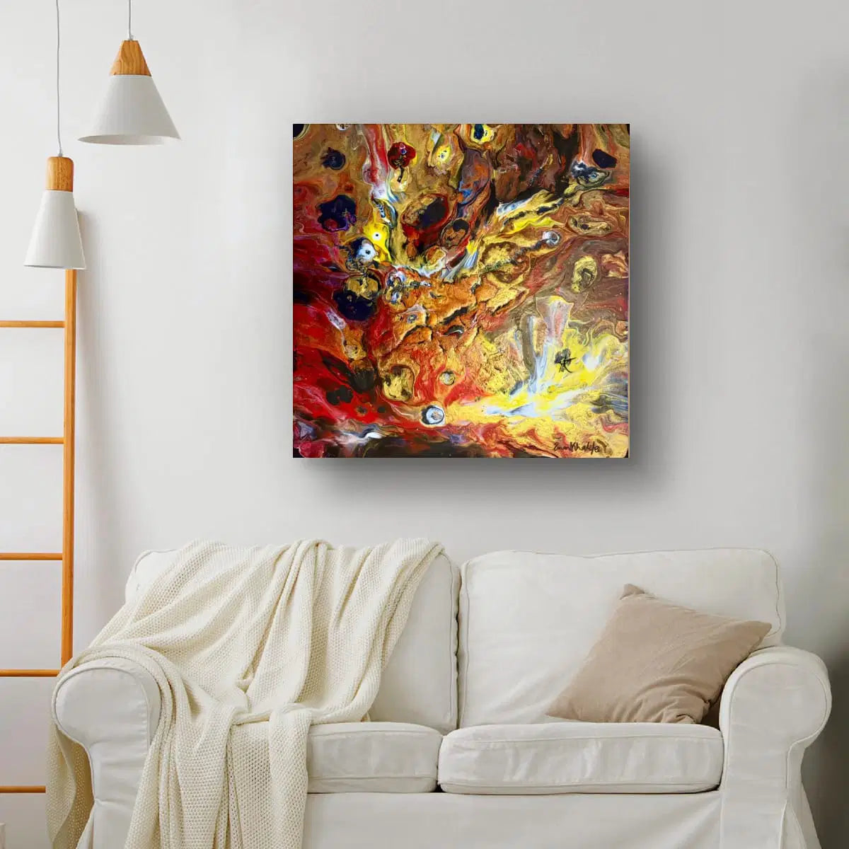 Abstract fire painting on a wall above a white sofa with a blanket and pillow.